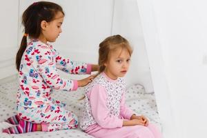 two little smiling lovely sisters in white bed, top, view photo