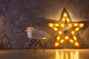 Star lamp on the background of an old wall, on the wooden floor, lights, lights, lights, glare. Exhibition star, light object, interior decor. Abstract dark background, night view, club photo