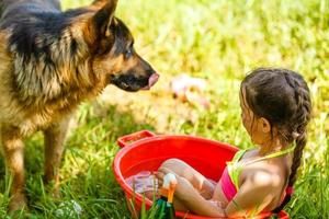 little girl sits in basin with water. Hot summer day photo