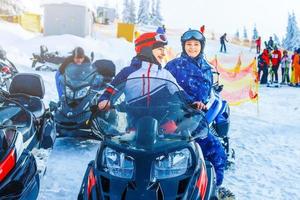 Beautiful girl sitting on a snowmobile at a ski resort photo