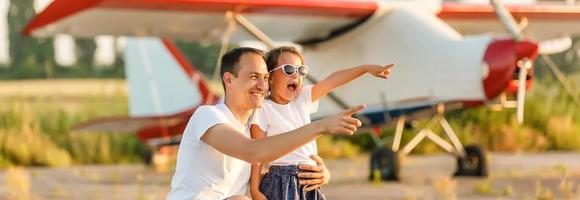 Father and daughter are happy with the plane on the meadow. photo