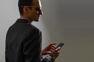 Businessman with smartphone, reading good news on internet at his mobile phone, wearing suit photo
