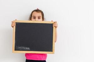 Little girl holding black board on white background photo