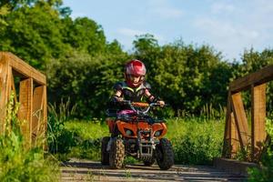 Little girl riding ATV quad bike in race track photo