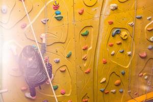 Little girl climbing a rock wall indoor photo