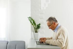 Old kind grandfather trying to use alone the internet. photo