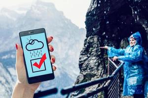 Female holding a smartphone and using Google Weather application on the screen photo