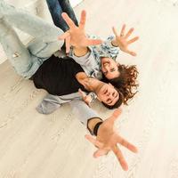 Happy young couple lying on the floor of new house and choosing color from palette photo