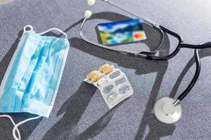 Surgical mask and stethoscope over gray background, view from above photo