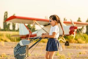 Child aviator with airplane dreams of traveling in summer in nature at sunset photo