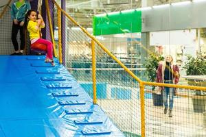 Adorable Little girl laughing happily, riding upside down on a bungee swing on the playground in yellow. Happiness, freedom, enjoyment, health. photo