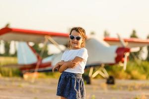 field with plane flying over it, little girl near the plane photo