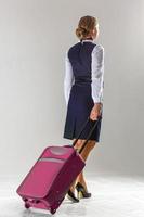 The stewardess goes and rolls her suitcase photo