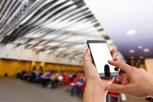 Man use mobile phone, blur image of people live in large conference room as background. photo