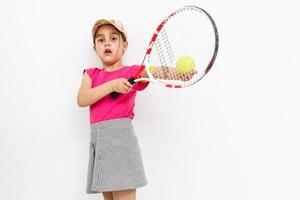 chica sosteniendo raqueta de tenis y pelota de tenis aislado en blanco. foto