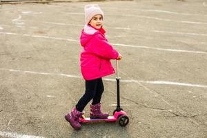 niño montando scooter. niño en tablero colorido. diversión activa al aire libre para niños. deportes de verano para niños en edad preescolar. niña en el parque de primavera. foto