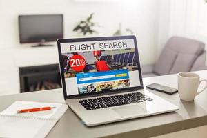 Flights online booking and reservation. Search flights on a computer laptop screen, office desk background. photo