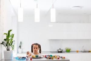 Little girl painting Easter eggs in the kitchen photo