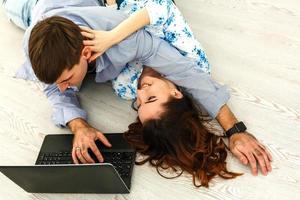 pareja comprando en línea en una computadora portátil - dos jóvenes amigos viendo un video en un cuaderno en la sala de estar foto