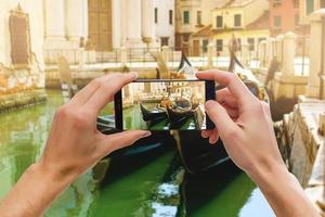 A mobile phone snapping a picture of a gondolier on his gondola in venice photo