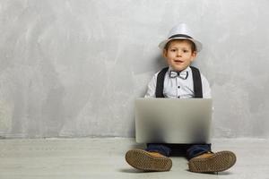 Young man sits on the laminate floor with black laptop. photo