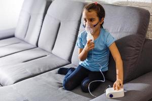 Little girl making inhalation with nebulizer at home. child asthma inhaler inhalation nebulizer steam sick cough concept Horizontal photo