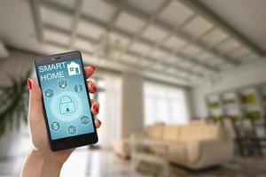 Smart home technology interface on smartphone app screen with augmented reality view of internet of things  connected objects in the apartment interior, person holding device photo