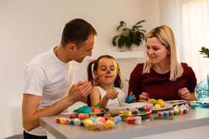 Happy easter family mother, father and children having fun paint and decorate eggs for holiday photo