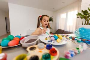 little girl having fun to paint easter eggs photo