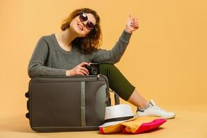 Ready for vacation. Traveling concept. Young excited woman sitting luggage valise. Isolated photo