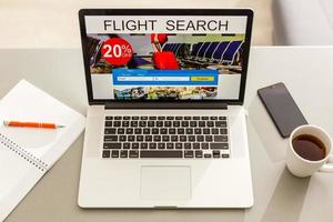 Flights online booking and reservation. Search flights on a computer laptop screen, office desk background. photo