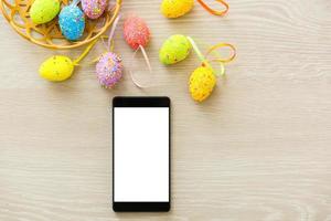 phone mockup with plants. invitation card with environment and quail eggs. easter eggs, ribbons and nest on white background photo