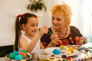 abuela con nieta están coloreando huevos para pascua. foto