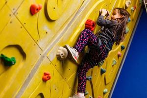 little girl climbing a rock wall indoor. photo