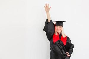 emocionada feliz estudiante graduada está de pie en el manto, sonriendo y mirando a la cámara foto