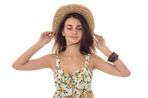 a charming young girl with closed eyes and stands up straight keeps hands hat on your head photo