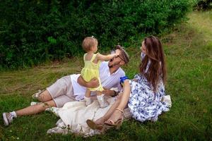 divertida familia caucásica con hija relajándose al aire libre en un cálido día de verano foto