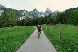 Back of man with backpack walking in mountains at Vorderer Gosausee, Gosau, Upper Austria. photo