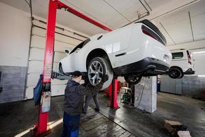 Two mechanic in service repair station working with muscle car in lift. photo