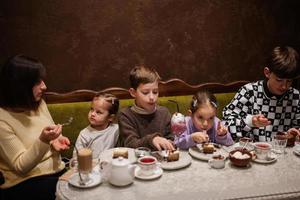 Happy family eating desserts together at cozy cafe and having fun. photo