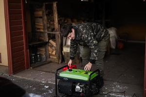 Man wear in military jacket with gasoline portable mobile backup standby generator. photo