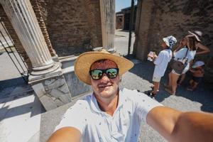 Man tourist in hat and sunglasses making selfie at Pompeii ancient city, Italy. photo