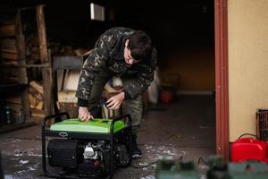 Man wear in military jacket with gasoline portable mobile backup standby generator. photo