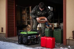 Man wear in military jacket with gasoline portable mobile backup standby generator. photo