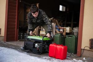 Man wear in military jacket with gasoline portable mobile backup standby generator. photo