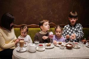 Happy family eating desserts together at cozy cafe and having fun. Boy kid drink milk shake. photo