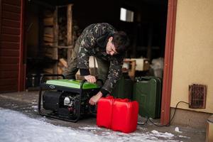 Man wear in military jacket with gasoline portable mobile backup standby generator. photo