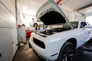 Muscle car with open hood at service repair station in lift. photo