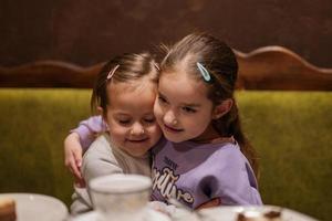 Sisters drink tea and  hugs together at cozy cafe and having fun. photo