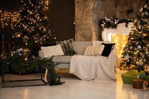 Stylish christmas living room interior with couch, white chimney, christmas tree and wreath, gifts and decoration. photo